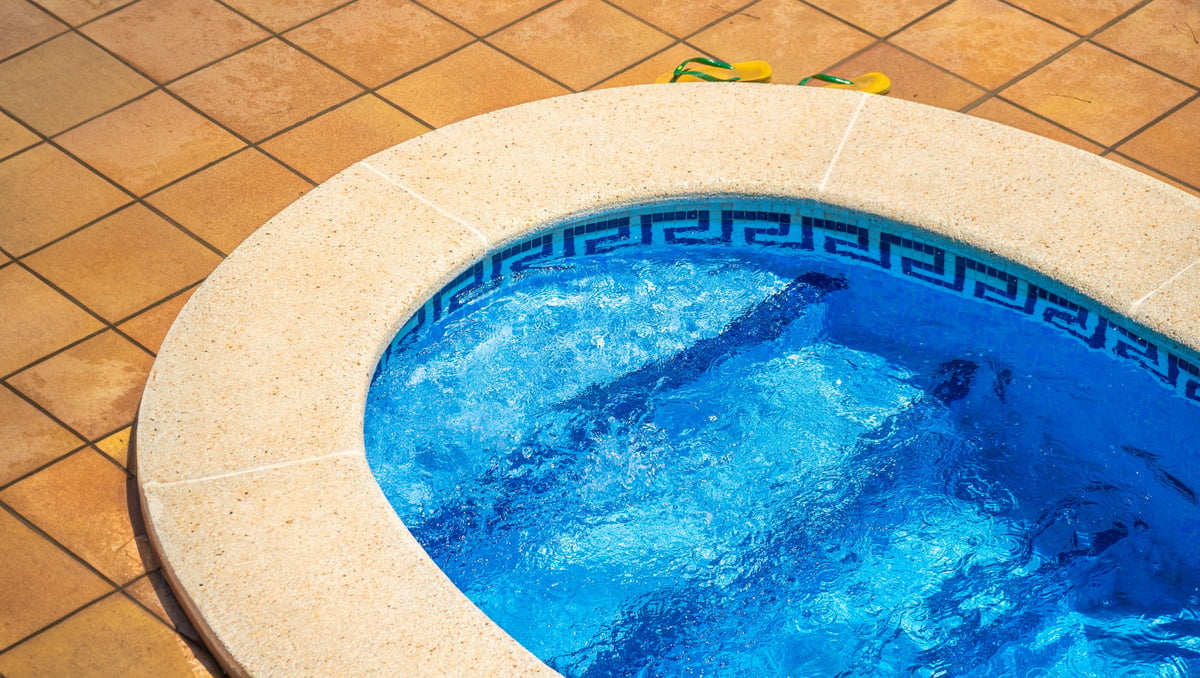 Piscina a medida con bordes de granito y azulejos azules