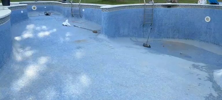 Empty residential swimming pool with light blue surface and maintenance equipment visible